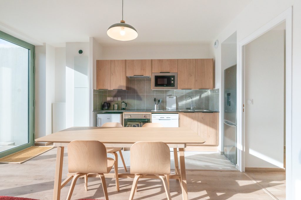 Cocina y comedor luminosos de un apartamento con mesa de madera