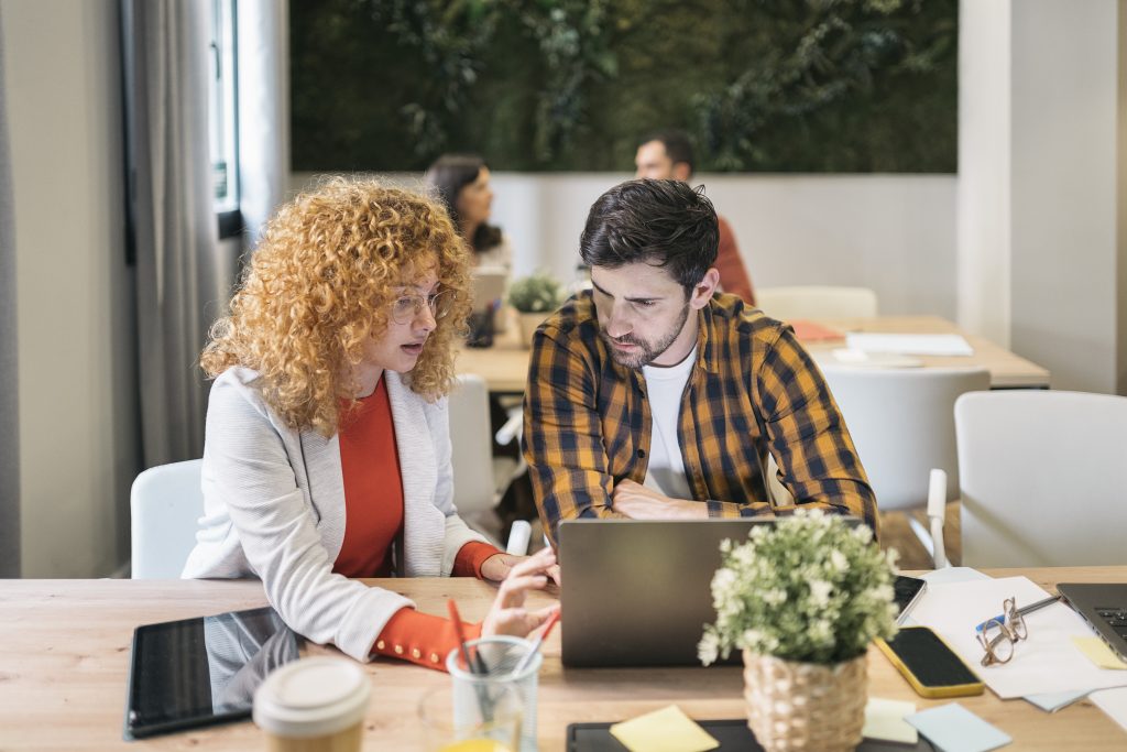 Dos profesionales trabajando con un portátil en una oficina compartida