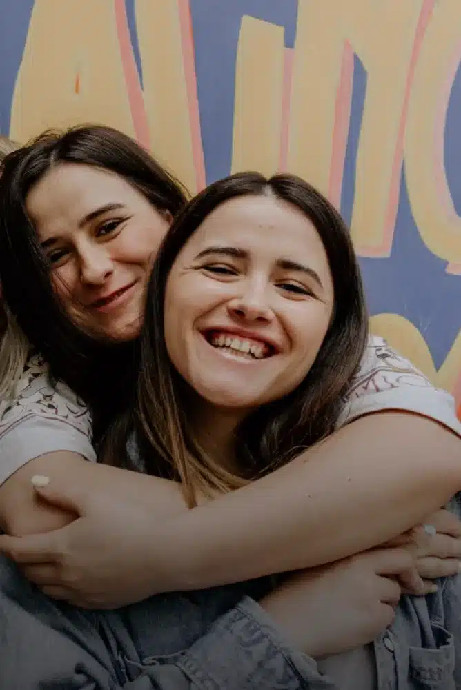 Residentes de Urban Campus sonriendo juntas frente a un mural colorido