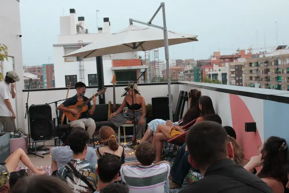 Acoustic duo performing on an Urban Campus rooftop, sunset atmosphere with residents gathered around