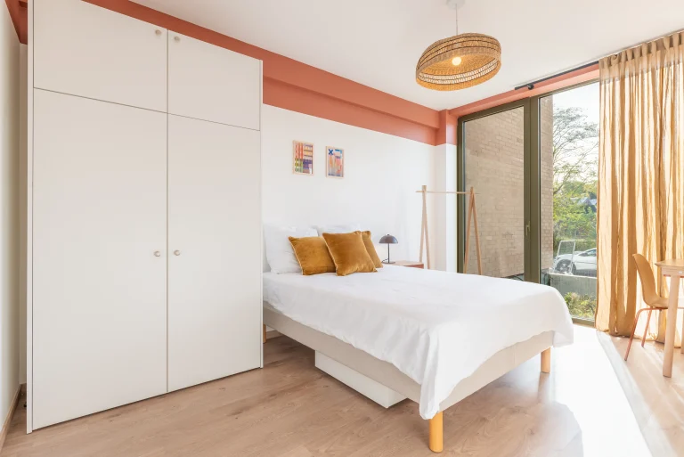 Bedroom with orange accent wall and wardrobe at Urban Campus La Maillerie Coliving in Lille