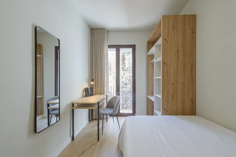 Bedroom with desk and balcony access at Urban Campus Avenida América Coliving in Madrid