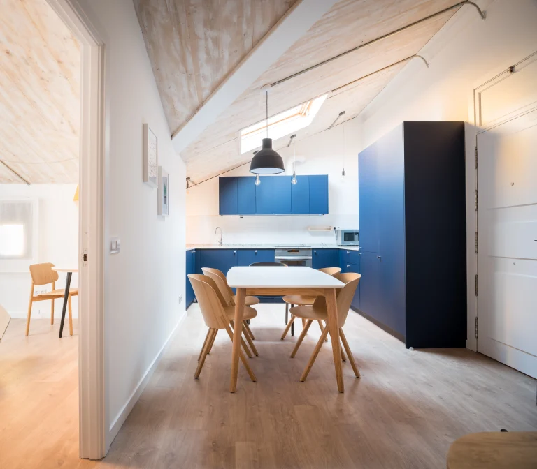 Kitchen and dining area at Urban Campus Malasaña Coliving in Madrid, blue cabinetry and skylight