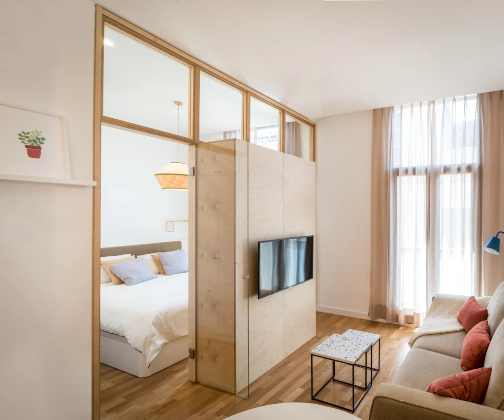 Living area at Urban Campus Malasaña Coliving in Madrid, sofa and bedroom nook with TV