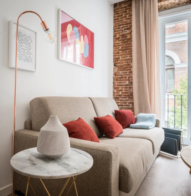Living room at Urban Campus Malasaña Coliving in Madrid, sofa against an exposed brick wall