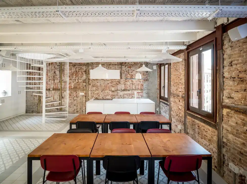Common kitchen at Urban Campus Malasaña Madrid, exposed brick walls and dining tables